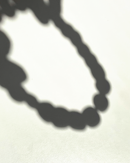 Reflejo minimalista del collar JASS capturado en un instante de luz.